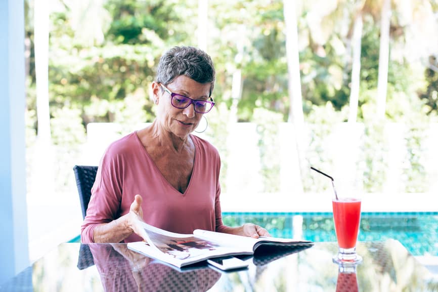 Senior woman reading a magazine at home about acupuncture