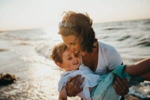 Woman with young son on beach demonstrates how happy you will feel after you get acupuncture for your jaw pain.