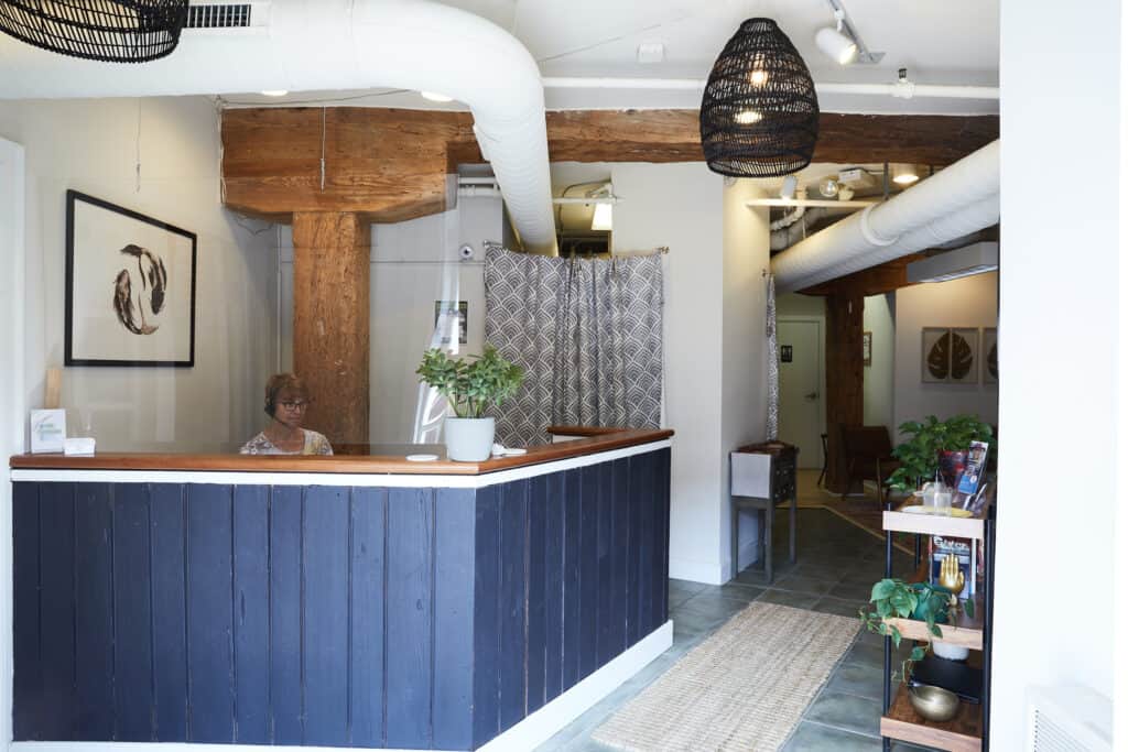 Centered Richmond Acupuncture waiting room with black desk and white walls, wooden beams.