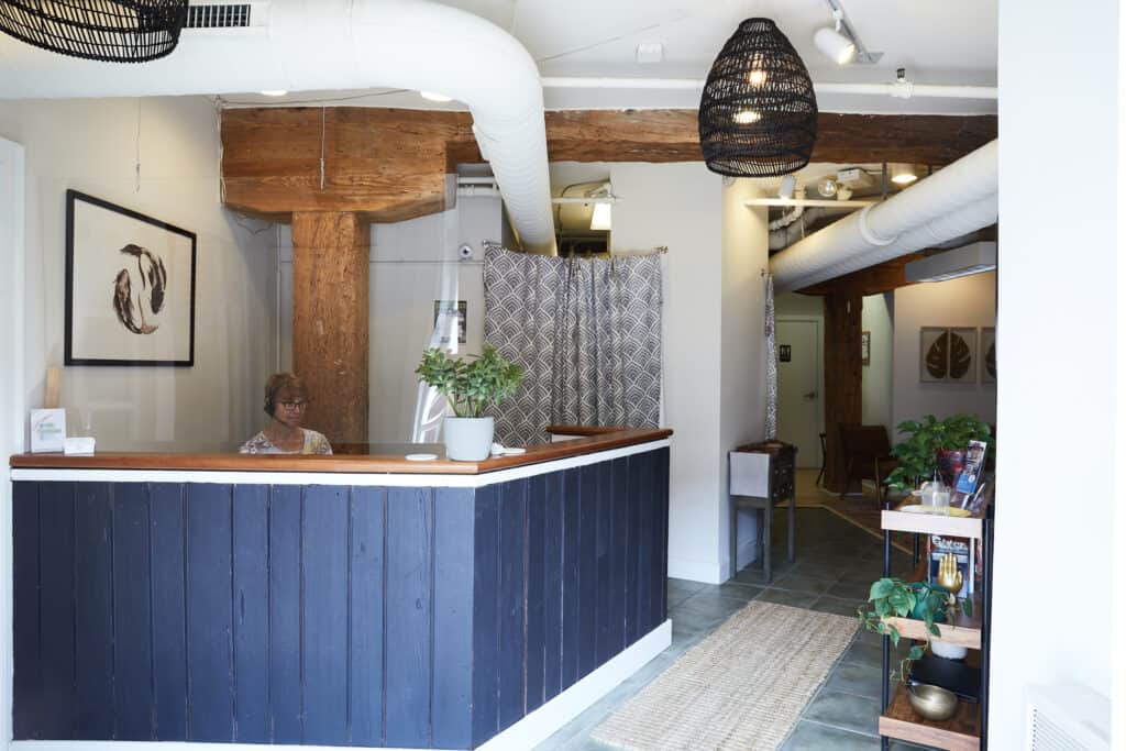 Centered Richmond Acupuncture waiting room with black desk and white walls, wooden beams. 